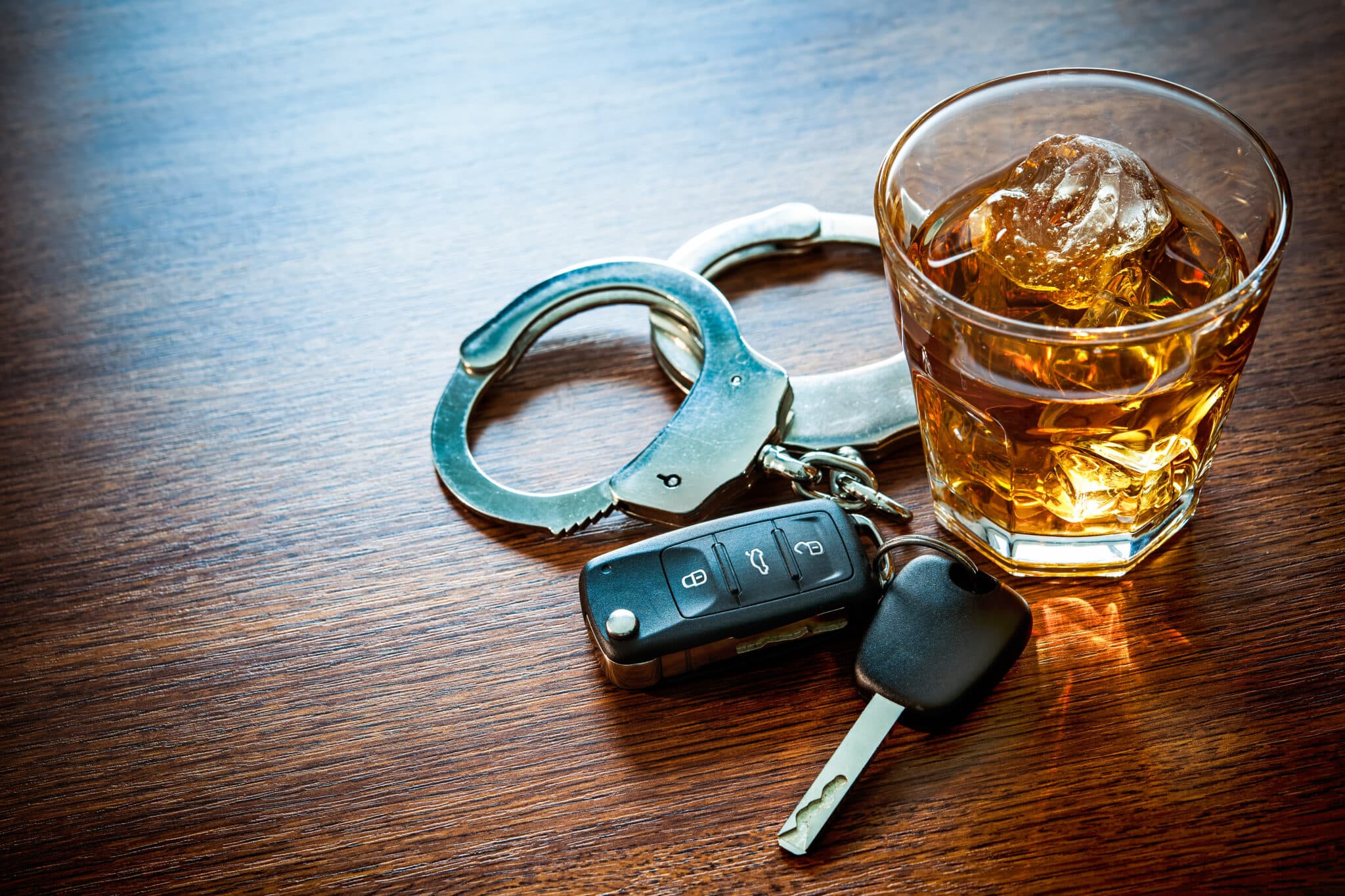 Alcohol next to keys and handcuffs –– call if you need can the best DWI or DUI criminal law firm in St. Louis